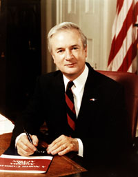 James Baxter Hunt, Jr. seated at desk with American flag in background.