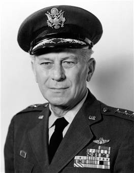 Armstrong from the chest up.  He is wearing his air force uniform coat, dress shirt, tie, and hat with eagle emblem on the front center above the bill.  He has a slight smile.